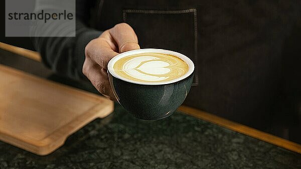 Close up Hand hält Kaffee mit Milchcreme