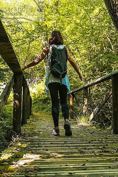 Mädchen mit Rucksack auf einer Holzbrücke im Naturpark Listorreta in der Stadt Errenteria im Park der Peñas de Aya oder Aiako Harria. Gipuzkoa  Baskenland