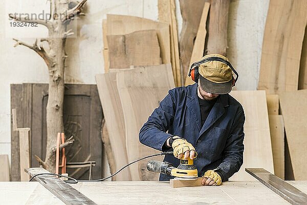 Nahaufnahme männlicher Schreiner mit elektrischer Schleifmaschine Holz