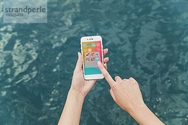Hand einer Frau  die ein Mobiltelefon mit einem Bildschirm für Benachrichtigungen über soziale Medien benutzt