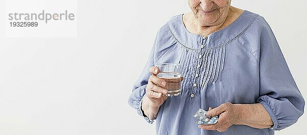Vorderansicht ältere Frau  die ihre Pillen nimmt  mit Kopierraum