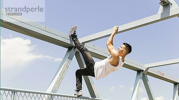 Seitenansicht junger Mann klettert auf Deckenbrücke