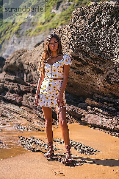 Porträt eines brünetten Mädchens in einem weißen Kleid am Strand  das den Sommer genießt