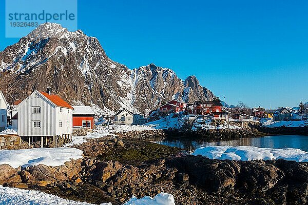 Alte traditionelle Fischerhütte namens Rorbu bei Svolvaer auf den Lofoten in Norwegen im Winter mit Schnee an einem klaren Tag mit blauem Himmel