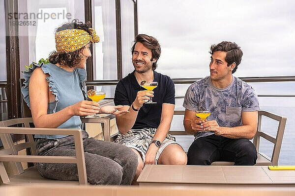 Drei entspannte Freunde  die ihren Urlaub mit Cocktails auf einer Terrasse feiern