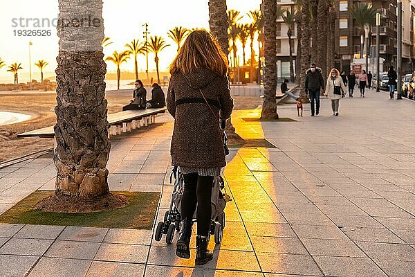 Mutter spaziert bei Sonnenuntergang am Playa del Cura in der Küstenstadt Torrevieja  Alicante  Valencianische Gemeinschaft. Spanien  Mittelmeer an der Costa Blanca