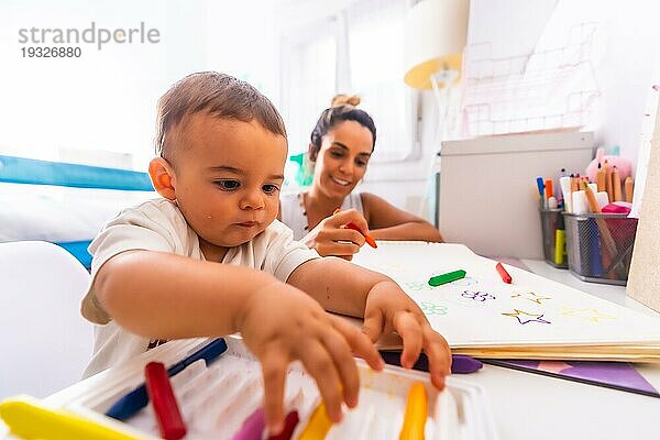 Junge kaukasische Mutter spielt mit ihr im Zimmer mit Spielzeug. Baby weniger als ein Jahr lernen die ersten Lektionen von ihrer Mutter. Malen mit Farbe malt
