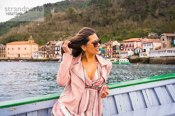 Hübsche lateinische Frau mit Sonnenbrille beim Sightseeing auf einem Boot entlang der Küste. Sommertourismus im Urlaub  Modell mit Spaß auf Ausflug