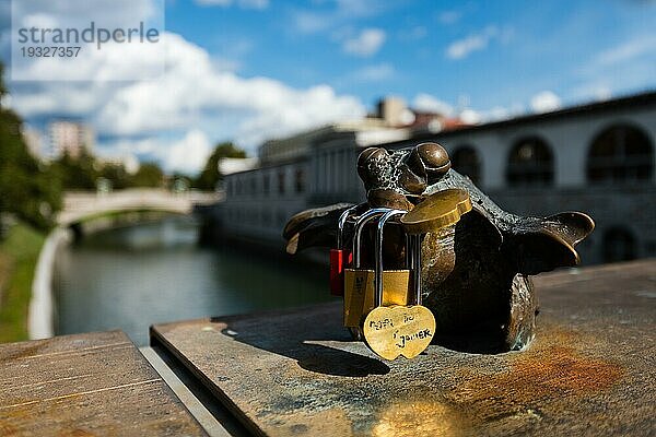 Verliebte Vorhängeschlösser an Figur auf Brücke über den Fluss Ljubljanica in Ljubljana an sonnigem Tag