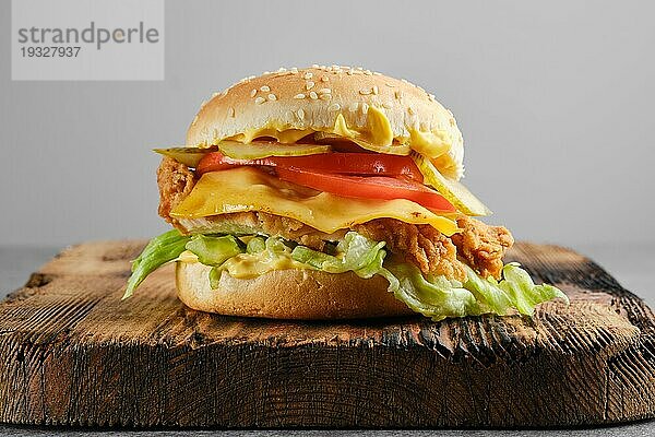 Chicken Cheeseburger mit frischem und eingelegtem Gemüse auf Holzuntergrund  Vorderansicht