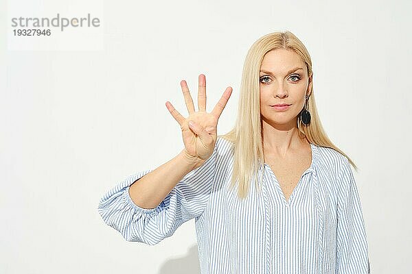 Attraktive blonde Frau zeigt vier Finger. Zählen mit Fingern