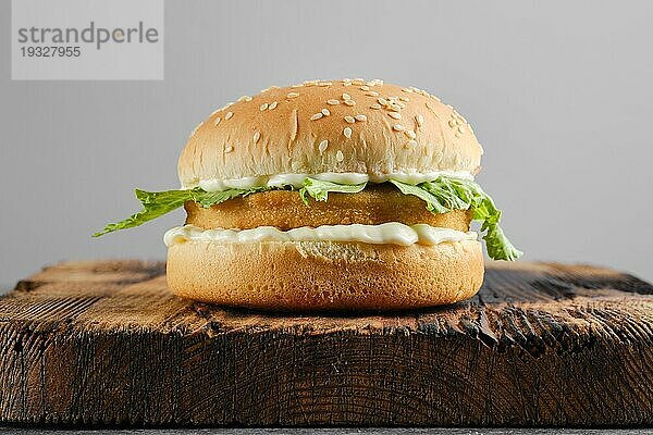 Hähnchenburger mit frischem Eisbergsalat auf Holzbrett  Vorderansicht