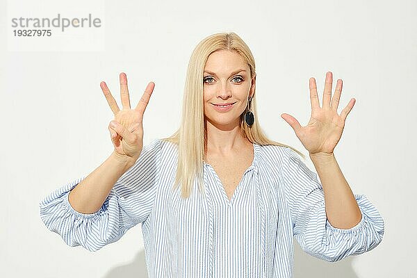 Attraktive blonde Frau zeigt acht Finger. Zählen mit Fingern