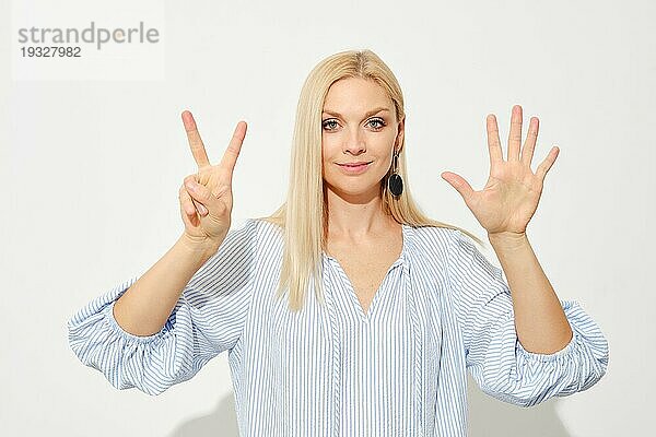 Attraktive blonde Frau zeigt sieben Finger. Zählen mit Fingern