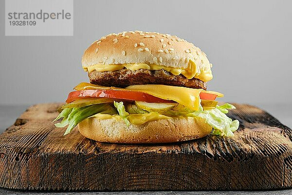 Rindfleisch Cheeseburger mit Gemüse und Käsesauce auf Holzbrett  Vorderansicht