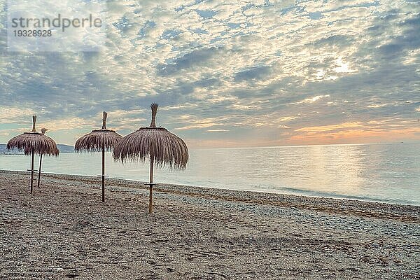 San Pedro Alcantara  Málaga  Spanien Meereslandschaft mit strohgedeckten Sonnenschirmen in der Morgendämmerung und ruhiger See