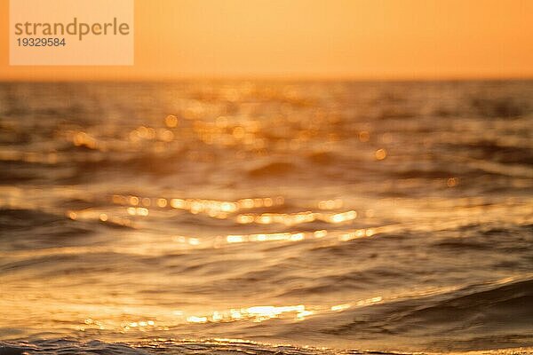 Ozean bei Sonnenuntergang im Gegenlicht mit Sonne defokussiert unscharfen Hintergrund