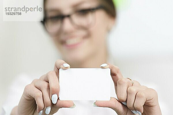 Geschäftsfrau s Hand zeigt leere weiße Visitenkarte in Richtung Kamera