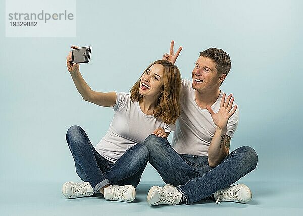 Junges Paar nimmt Selfie Handy gegen blaün Hintergrund