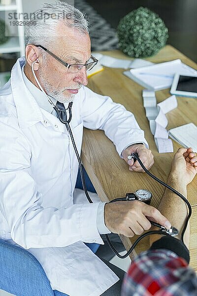 Seriöser Arzt mißt Blutdruck eines Patienten