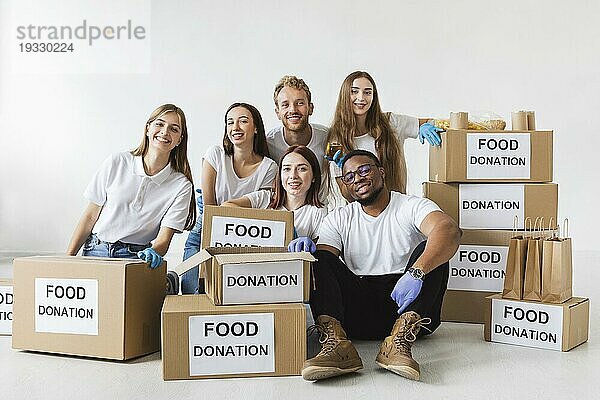 Lächelnde Freiwillige posieren zusammen mit Spendendosen mit Lebensmitteln
