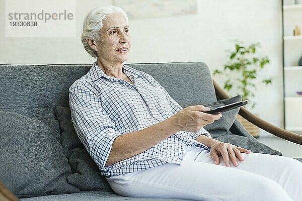 Ältere Frau beim Fernsehen mit Fernbedienung