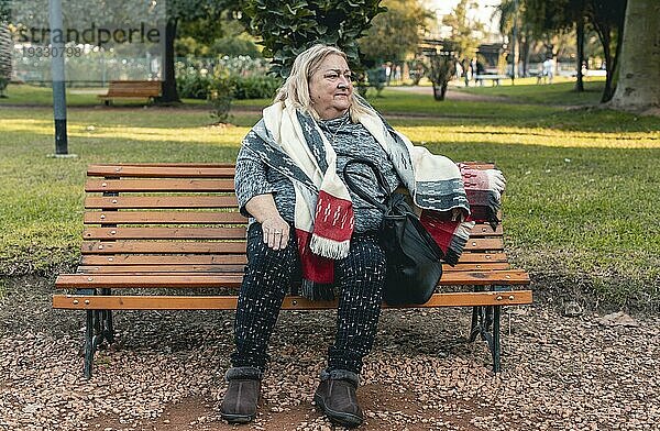 Ältere ernste Frau wartet auf jemanden  der auf einer Bank in einem öffentlichen Park sitzt