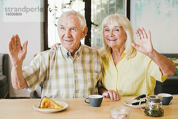 Freundliches älteres Ehepaar winkt mit den Händen