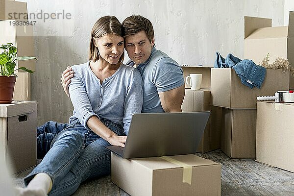 Glückliches Paar zu Hause mit Boxen Laptop bereit ausziehen