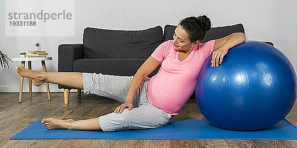 Smiley schwangere Frau zu Hause mit Gymnastikballmatte