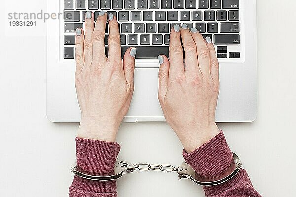 Draufsicht Hände mit Handschellen am Laptop