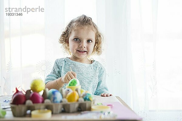 Mädchen färbt Eier und schaut in die Kamera