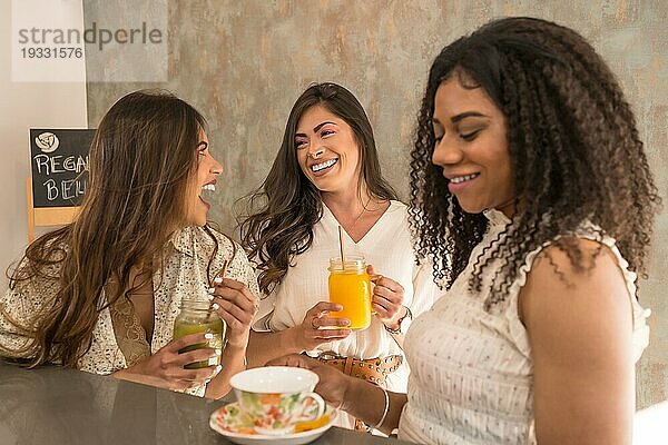 Lustige Momente von drei Frauen  die in einer gesunden Cafeteria lachen und sich amüsieren