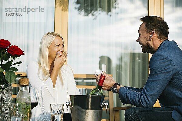 Überrascht junge Frau suchen Mann geben Verlobungsring Restaurant