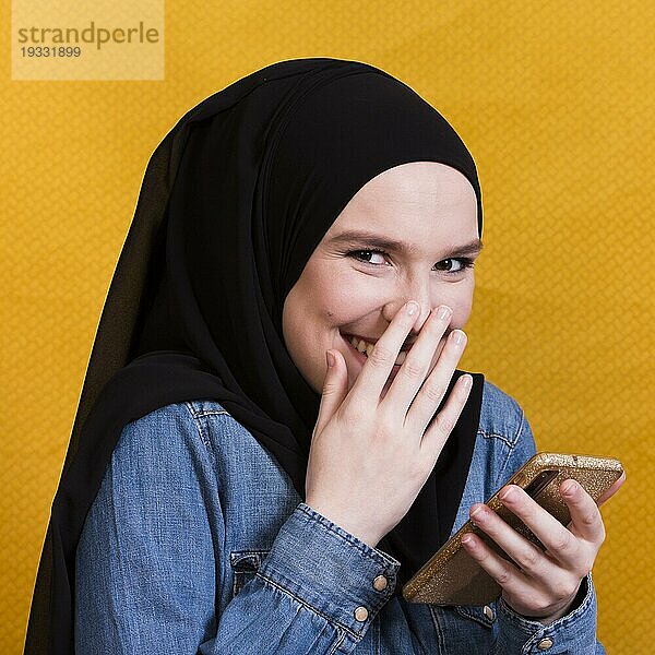 Glückliche Frau trägt Jeanshemd mit Smartphone hellen Hintergrund