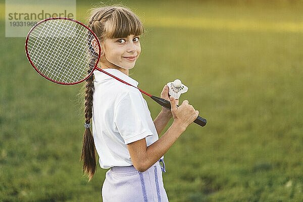 Lächelndes Mädchen hält Badminton Federball auf ihrer Schulter