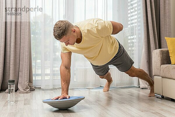 Seitenansicht Mann trainiert zu Hause mit Bosu Ball