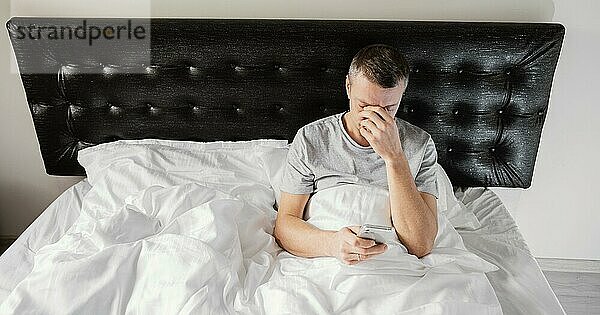 Mann im Bett mit Handy