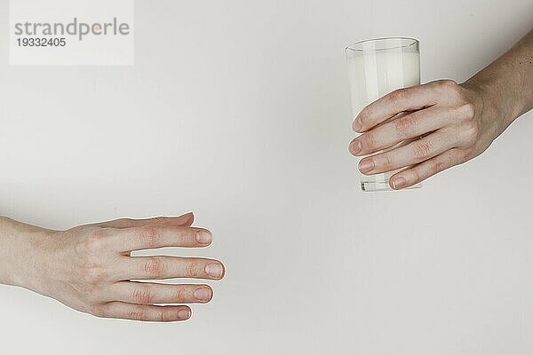 Person  die einem anderen ein Glas Milch reicht