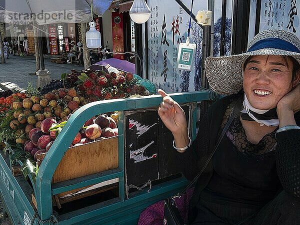 Lachende Verkäuferin  exotische Früchte auf Anhänger in den Straßen von Dali  Yunnan  China  Asien