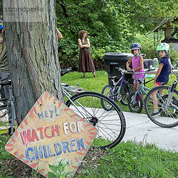 Detroit  Michigan  Ein Schild warnt Autofahrer  auf Kinder zu achten  während sich junge Fahrradfahrer zum Start des Farnsworth Criterium versammeln  einer Fahrradparade für Kinder  die auf der Farnsworth Street im Osten von Detroit stattfindet