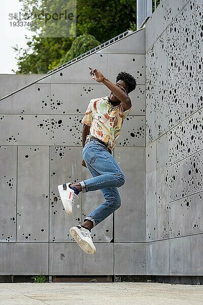 Vertikales Foto eines afrikanisch amerikanischen Mannes  der im Freien hoch springt
