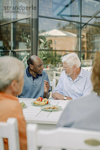 Ältere Männer reden miteinander  während sie am Esstisch sitzen