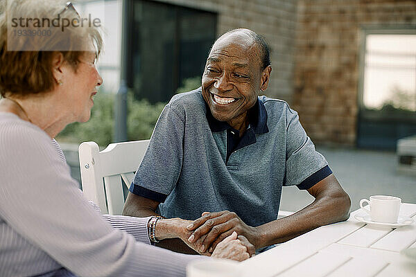 Glücklicher älterer Mann  der mit einer Frau spricht  während er am Esstisch sitzt