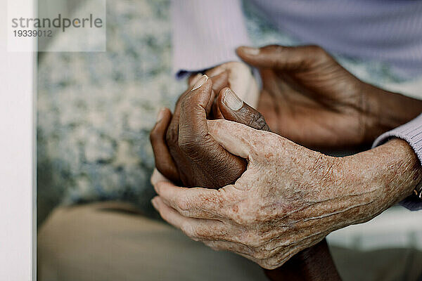 Ausgeschnittenes Bild eines älteren Mannes und einer älteren Frau  die sich an den Händen halten