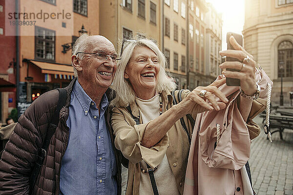 Glückliche Seniorin macht Selfie mit Mann in der Stadt