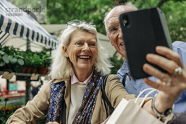 Glückliche Seniorin macht Selfie mit Mann per Smartphone
