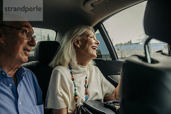 Fröhliches Seniorenpaar genießt Taxifahrt in der Stadt