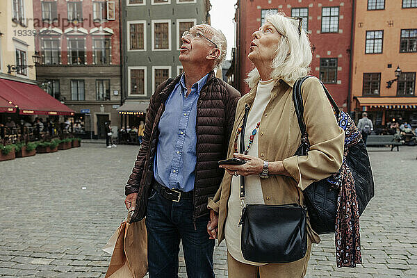 Erstauntes älteres Paar blickt auf  während es zusammen in der Stadt steht