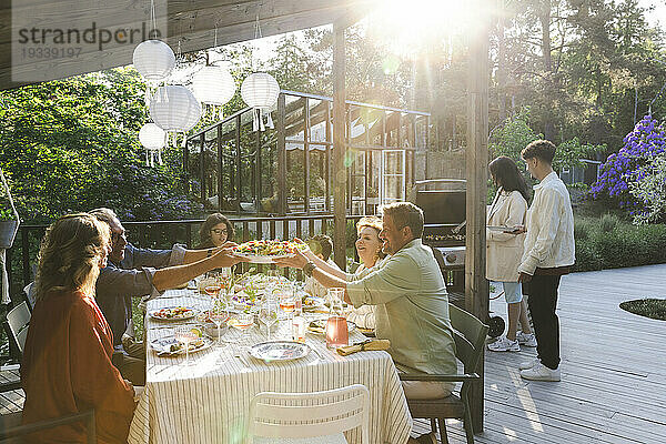 Familie und Freunde genießen ein Sommeressen auf der Terrasse im Hinterhof